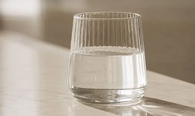 یک لیوان دنده‌دار از Kangen Water® شفاف روی پیشخوانی در نور آفتاب